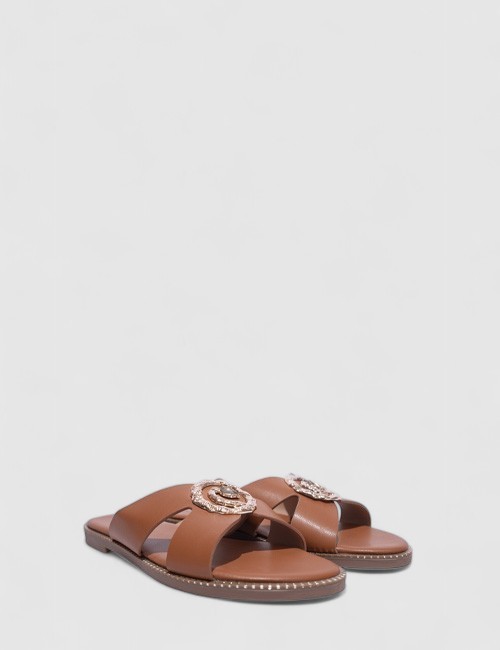 Cette image contient Mules Plates en Cuir Cognac avec Ornements chez Joliesse. à 59,99 TND en Tunisie. L'hexa de l'arrière plan 