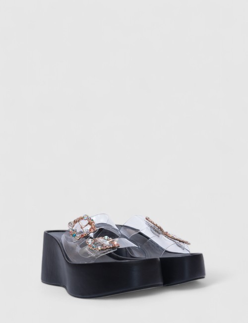 Cette image contient Sandales compensées transparentes avec strass multicolores chez Joliesse. à 99,99 TND en Tunisie. L'hexa de