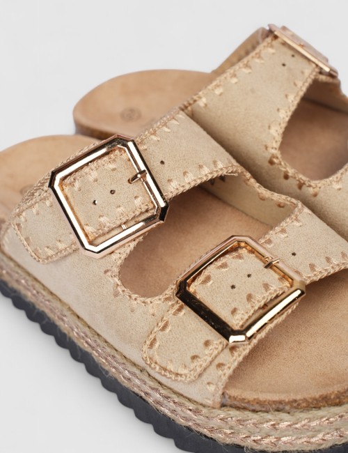 Cette image contient Mules en suédine beige avec boucles dorées chez Joliesse. à 0,00 TND en Tunisie. L'hexa de l'arrière plan e