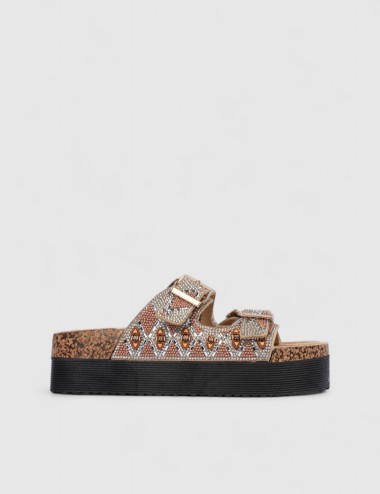 Cette image contient Mules femme motif ethnique strass et boucles dorées chez Joliesse. à 0,00 TND en Tunisie. L'hexa de l'arriè
