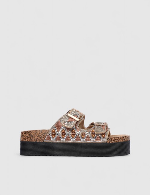 Cette image contient Mules femme motif ethnique strass et boucles dorées chez Joliesse. à 0,00 TND en Tunisie. L'hexa de l'arriè
