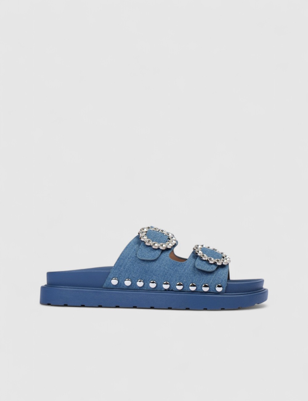 Cette image contient Mules denim bleu à boucles strass et semelle épaisse chez Joliesse. à 0,00 TND en Tunisie. L'hexa de l'arri
