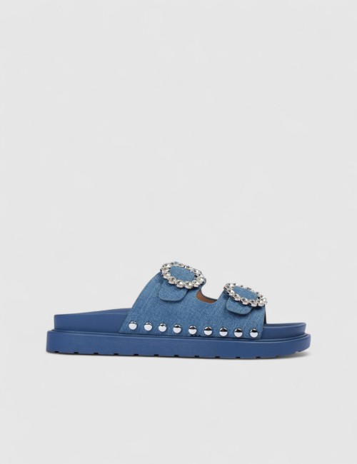 Cette image contient Mules denim bleu à boucles strass et semelle épaisse chez Joliesse. à 0,00 TND en Tunisie. L'hexa de l'arri