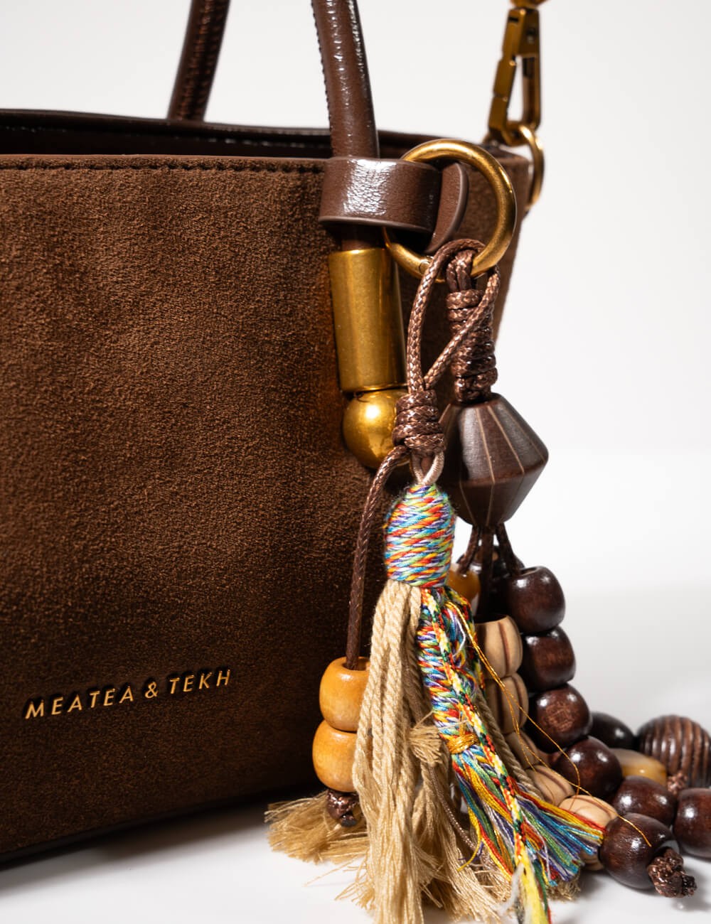 Cette image contient Sac à Main en Daim Marron avec Pompon chez Joliesse. à 129,99 TND en Tunisie. L'hexa de l'arrière plan est 