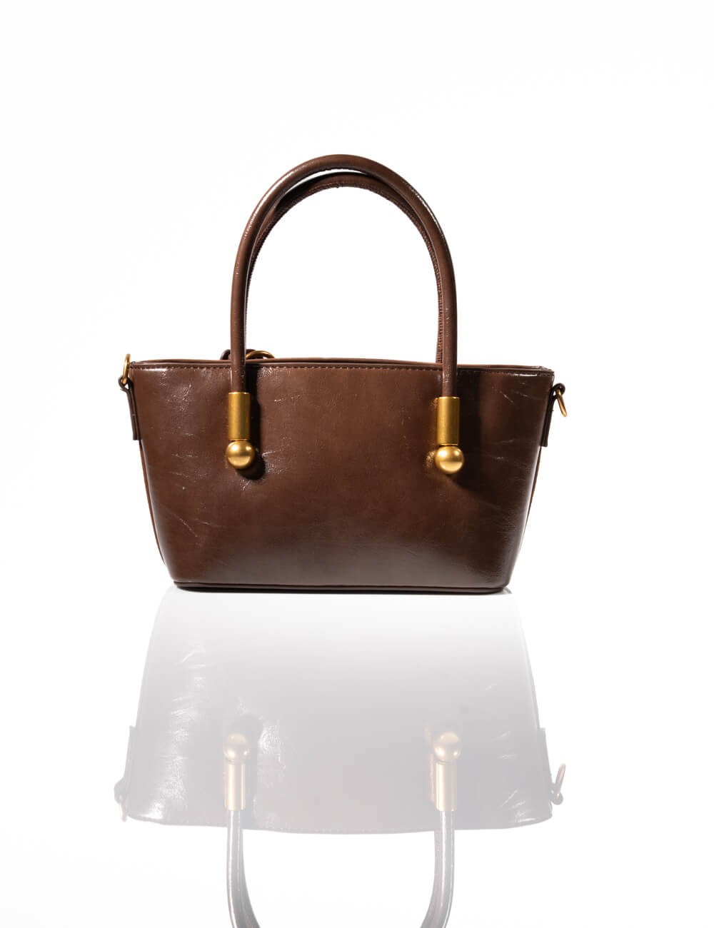 Cette image contient Sac à Main en Daim Marron avec Pompon chez Joliesse. à 129,99 TND en Tunisie. L'hexa de l'arrière plan est 