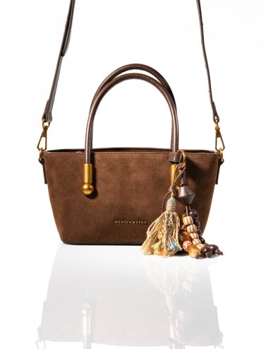 Cette image contient Sac à Main en Daim Marron avec Pompon chez Joliesse. à 129,99 TND en Tunisie. L'hexa de l'arrière plan est 